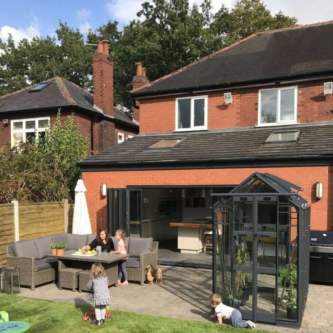 Cottage 4 greenhouse placed beside a home patio with open double doors and kids playing nearby