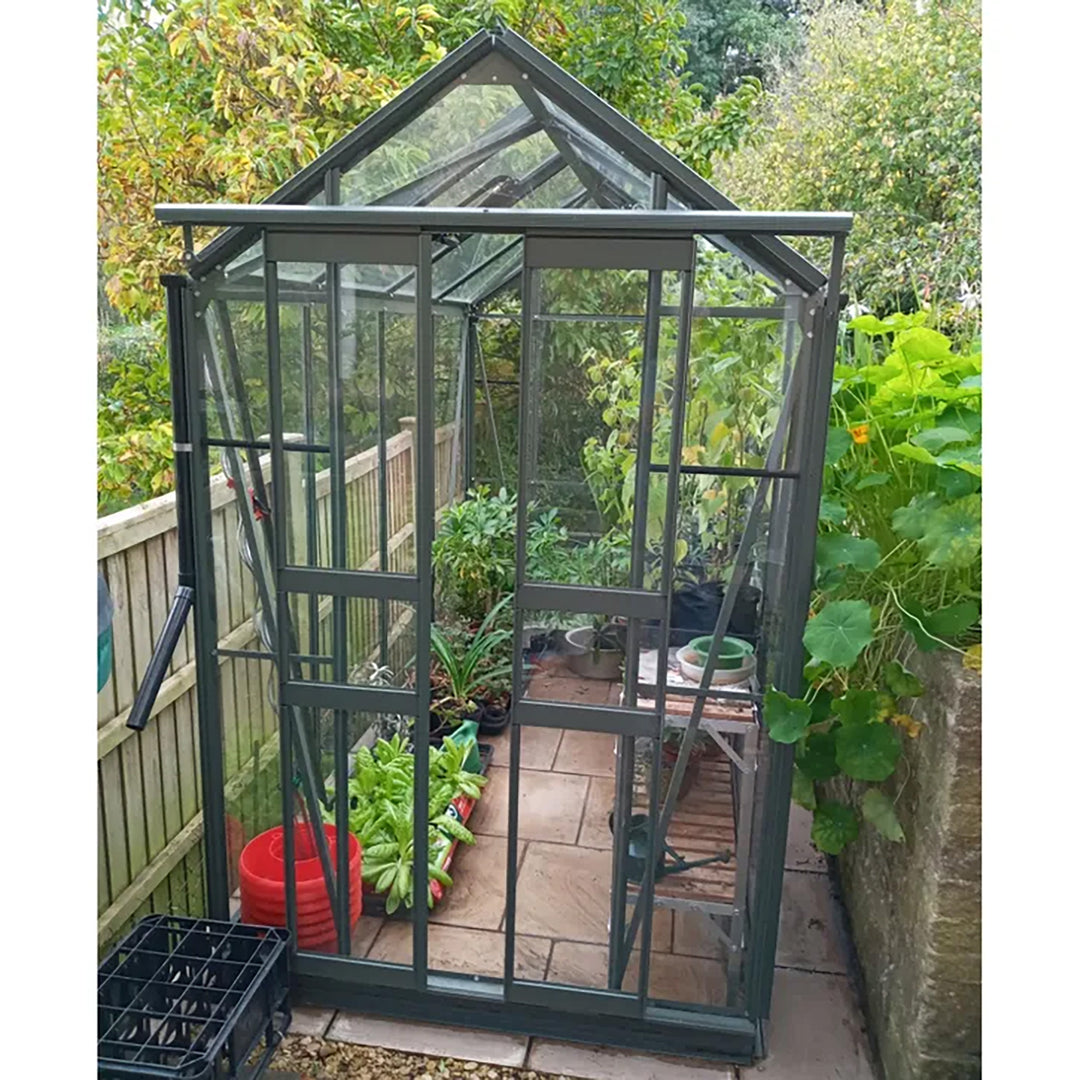 Cottage 8 greenhouse filled with leafy greens and potted vegetables, nestled in a compact garden space